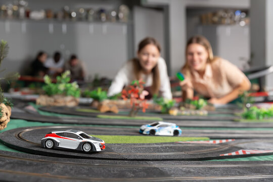 Portrait of two women playing with slot car racing track. High quality photo