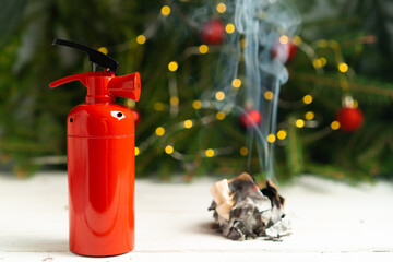 The fire extinguisher stands on a white table, against the background of a Christmas tree and...