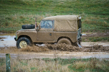 a Land Rover vehicle driving off-road through deep muddy water Salisbury Plain UK