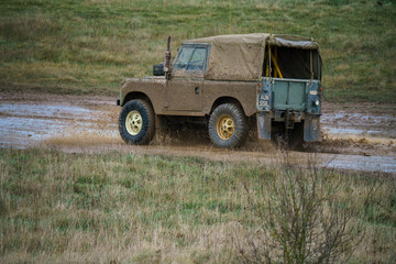 a Land Rover vehicle driving off-road through deep muddy water Salisbury Plain UK