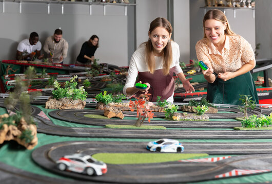 Portrait of two girls playing with slot car racing track. High quality photo