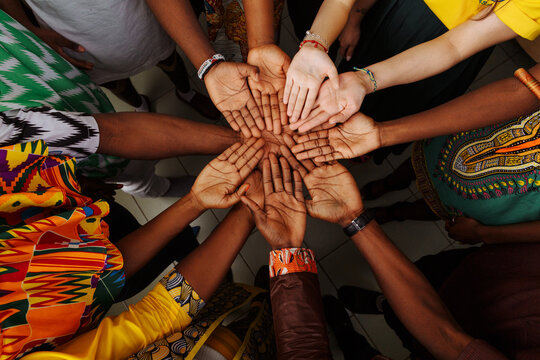 Palms up hands of a happy group of multinational African, Latin American and European people who stay together in a circle