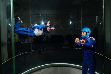 A man teaches a boy to fly in a wind tunnel.