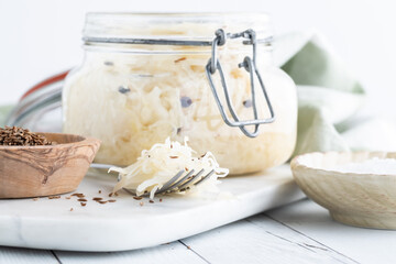 Close up of a jar of fresh sauerkraut with a fork heaping full in front.