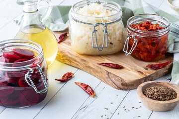 Glass jars of preserves including beets, sauerkraut and sundried tomatoes.