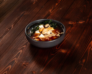 Food, soup with rice, mussels, tofu cheese, seaweed, sesame seeds in a plate on a dark wood background