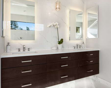 Beautiful Bathroom Vanity In New Luxury Home. Double Vanity With Undermount Sinks, Sconce Lights, Floating Cabinets, Mirrors, And Elegant Backsplash.