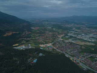 Obraz premium Drone shot of residential area near green mountains range at Chemor, Ipoh, Perak, Malaysia.
