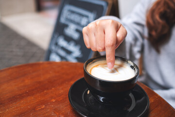 Fototapeta na wymiar Closeup of a woman pointing at a hot coffee