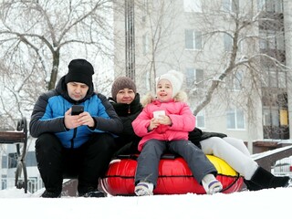 Obraz premium Young family on a winter family vacation. Little child girl with a cup of warm cocoa outdoors for Christmas. Alternative to computer games.