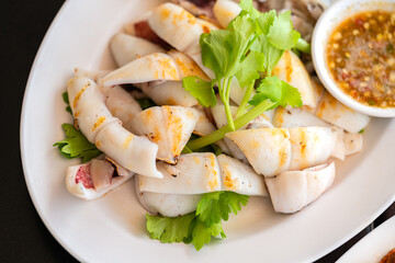 Grilled fresh squid, Close up Thai food Grilled fresh squid in white plate with spicy and sour sauce or seafood sauce, top view image.