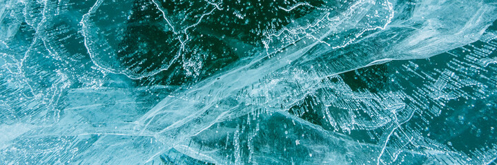 Texture of beautiful blue ice with cracks and air bubbles in the frozen lake. Winter nature...