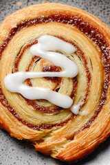 Fresh baked flaky cinnamon swirl pastry with sweet white fondant icing