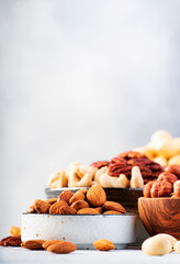 Nuts in bowls. Cashews, hazelnuts, walnuts, pecans, almonds and other. Healthy food snack mix on gray table background, copy space