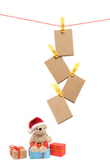 Small teddy bear in a Santa Claus hat sits on boxes with Christmas gifts.On a white background.