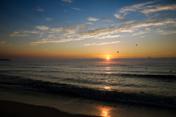 Gentle waves while the sun is rising over the Black Sea in the Obzor resort in Bulgaria on a calm and warm summer day.