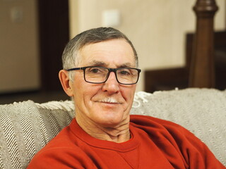 Portrait of a happy senior man sitting on the sofa at home.