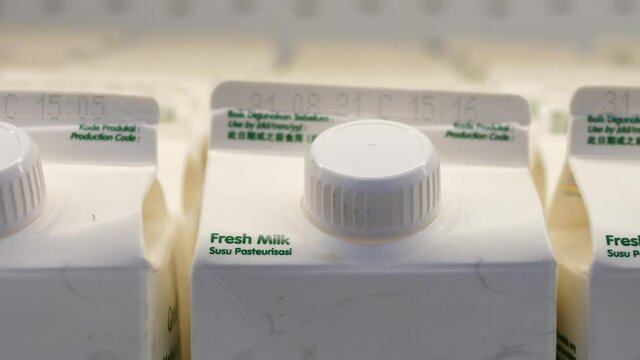 Close up of many fresh milk white boxes in a row in the supermarket fridge 