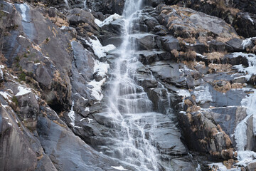 Fototapeta na wymiar Falling water from a cliff, waterfall. Falling water down winter. Icy water flows down the rocks.
