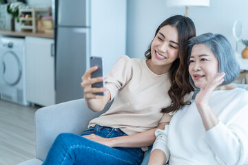 Asian happy family, senior mom use mobile phone with daughter at home. 