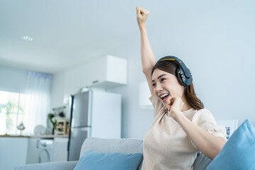 Asian funny woman listen to music and dance on floor in living room.