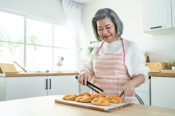 Portrait of Asian happy Senior elderly woman stand in kitchen at home.