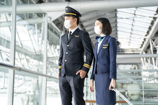 Portrait of Asian airliner pilot and air hostess wear mask and smile. 