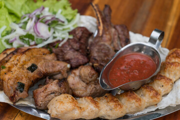 Assorted delicious grilled meat with lettuce and onion. Mixed grilled bbq meat with tomato sauce.Lamb, chicken. Top view, close up with copy space.