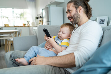 Caucasian loving father watch movie with baby in living room at home. 