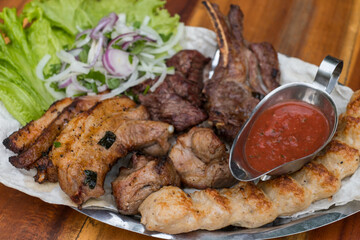Assorted delicious grilled meat with lettuce and onion. Mixed grilled bbq meat with tomato sauce.Lamb, chicken. Top view, close up with copy space.