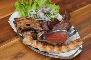 Assorted delicious grilled meat with lettuce and onion. Mixed grilled bbq meat with tomato sauce.Lamb, chicken. Top view, close up with copy space.