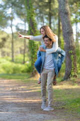 young happy couple enjoying piggyback ride at the park