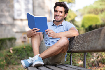Fototapeta premium young man reading a book in the park