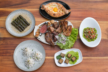 Assorted of different dishes. Georgian, Armenian and Russian cuisine. Ajara khachapuri, dolma, salad Olivier, Eggplant rolls, Khinkali, grilled meat 