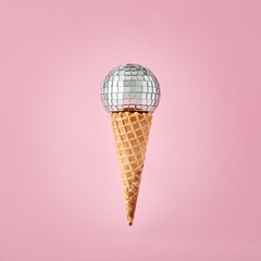 Disco ball on ice cream cone on pink background. Party and fun.