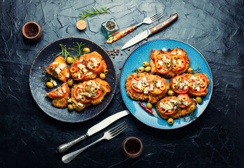 Fried schnitzel with olives and tomato