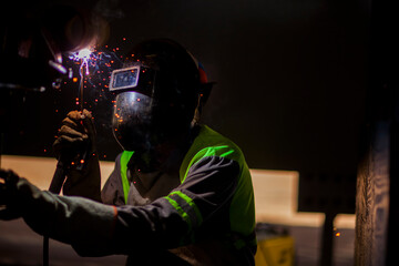 Fototapeta na wymiar Man works on metal welding steel using electric welding machine to weld. High quality photo