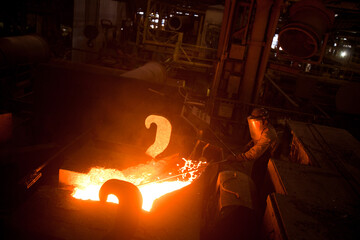 Hot metal is poured from the bowl into a special form in a steel factory. High quality photo.