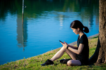 Asian woman waring a black dress sitting after jogging in the park