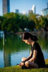Fototapeta na wymiar Asian woman waring a black dress sitting after jogging in the park