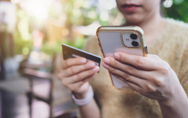 Woman hand holding credit card and smartphone for paying online using banking service. Online shopping concept