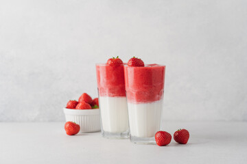 Protein rich smoothies with yogurt and frozen strawberries in glass on light background. Side view of healthy morning berry breakfast