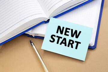 a new start is written on a blue plate that lies on open notebooks. Time to take action