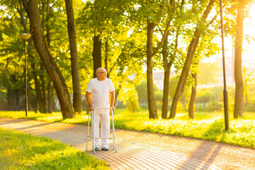 Old man is walking with walker outdoor at sunset. Rehabilitation concept.