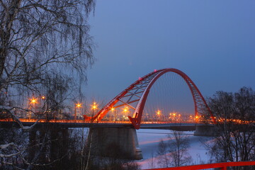 Fototapeta na wymiar red arch of the cable-stayed bridge in winter at night in novosibirsk