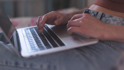A girl works from home, female hands on a laptop keyboard close-up