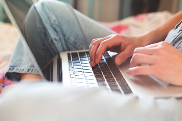 A girl works from home, female hands on a laptop keyboard close-up