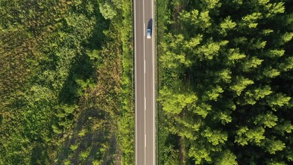 Drone pov shot of two cars passing by each other on road through green countryside landscape