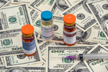 vaccine flasks with syringes lie on dollar bills.