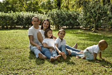 Portrait of happy parents with their three children lying in the park. The eldest daughter is a transgender girl. Concept of family happy united family with children.
